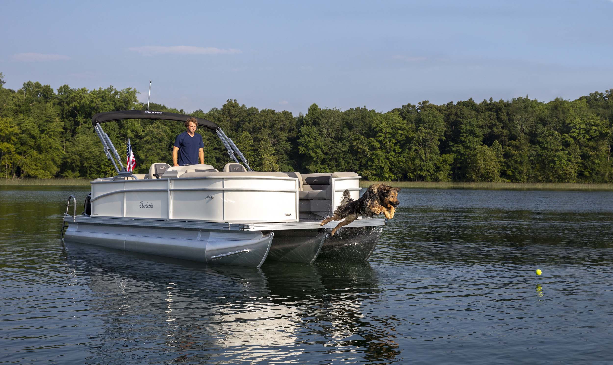 A man standing at a dock waving down a group of four bringing their 2018 Premier Horizon 220 …